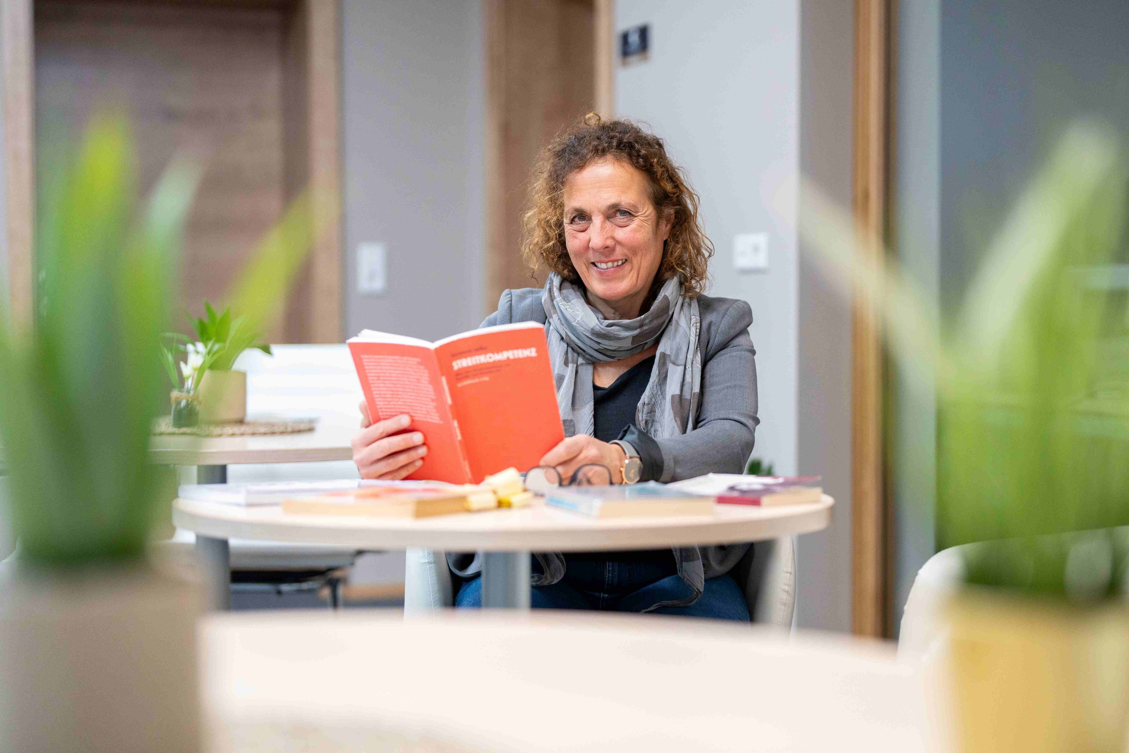 Birgit Seymann am Schreibtisch in ihrem Büro beim Lesen des Buches Streikompetenz von Susanne Jalka